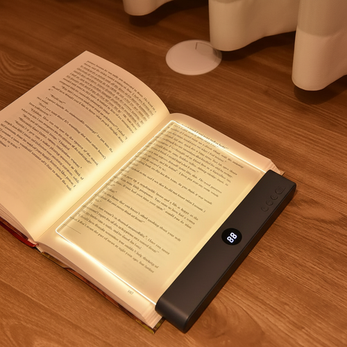 Black acrylic flat book night light glowing beside an open book